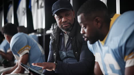 football coach and player discuss strategy in locker room