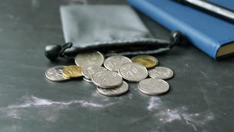 Close-up-of-coins-spilling-from-a-bog-on-table