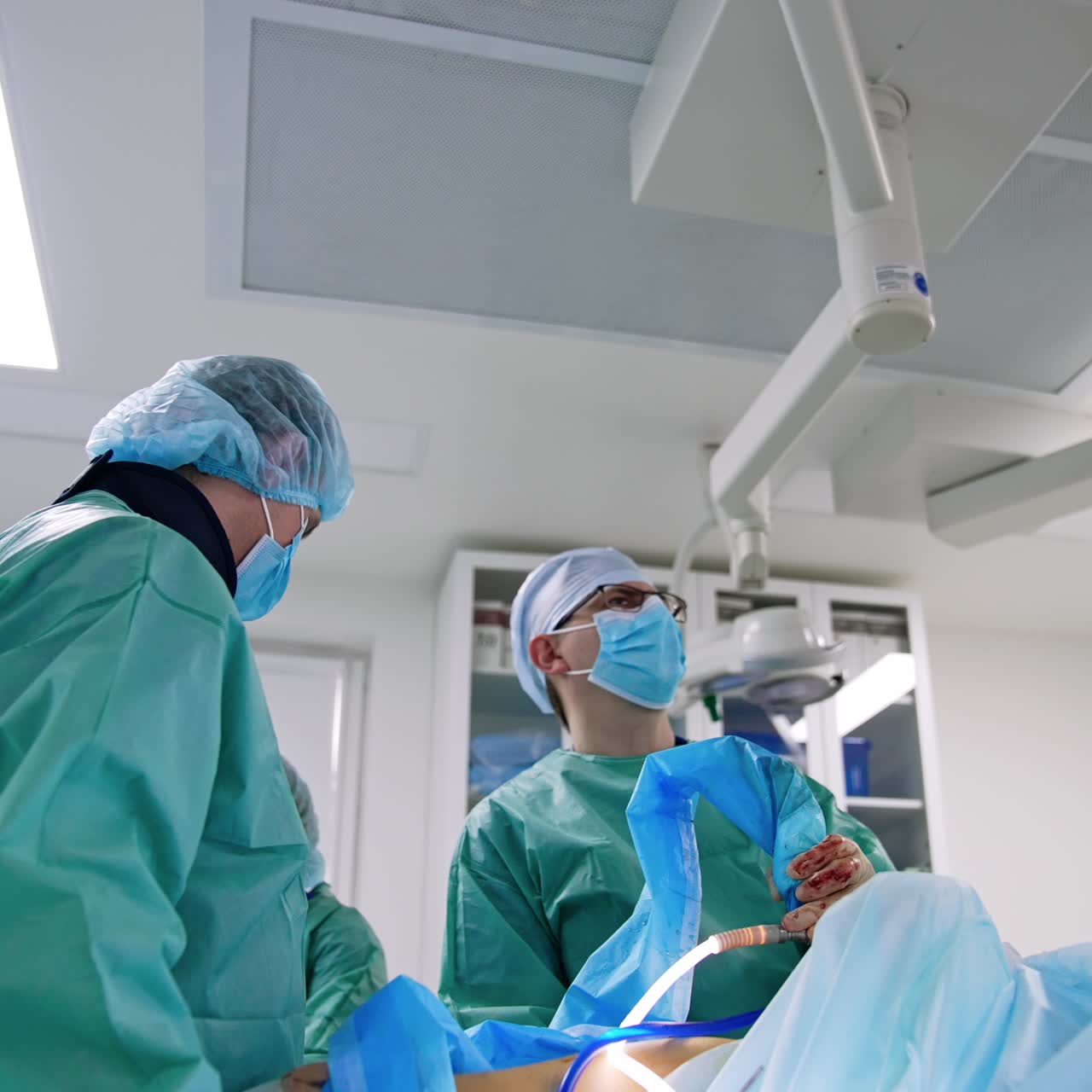 Professional surgeons hold modern surgical devices at operation. Specialists look intently on the monitor in front of them