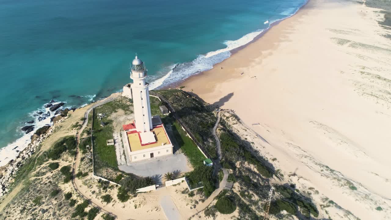 toma aérea de drones moviéndose hacia adelante y pasando por un faro en una orilla cerca de la playa