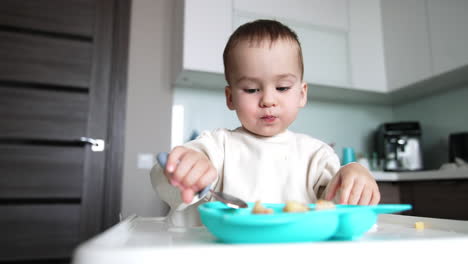 little kid eating from plate using spoon. baby is growing , developing and learning.