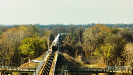 Train-crossing-bridge-in-West-Memphis-with-autumn-trees,-Delta-Regional-River-Park,-daytime,-wide-shot