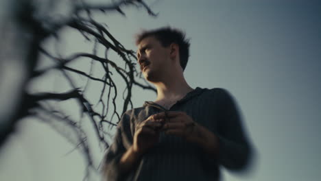 man with mustache outdoors under sky with tree branches