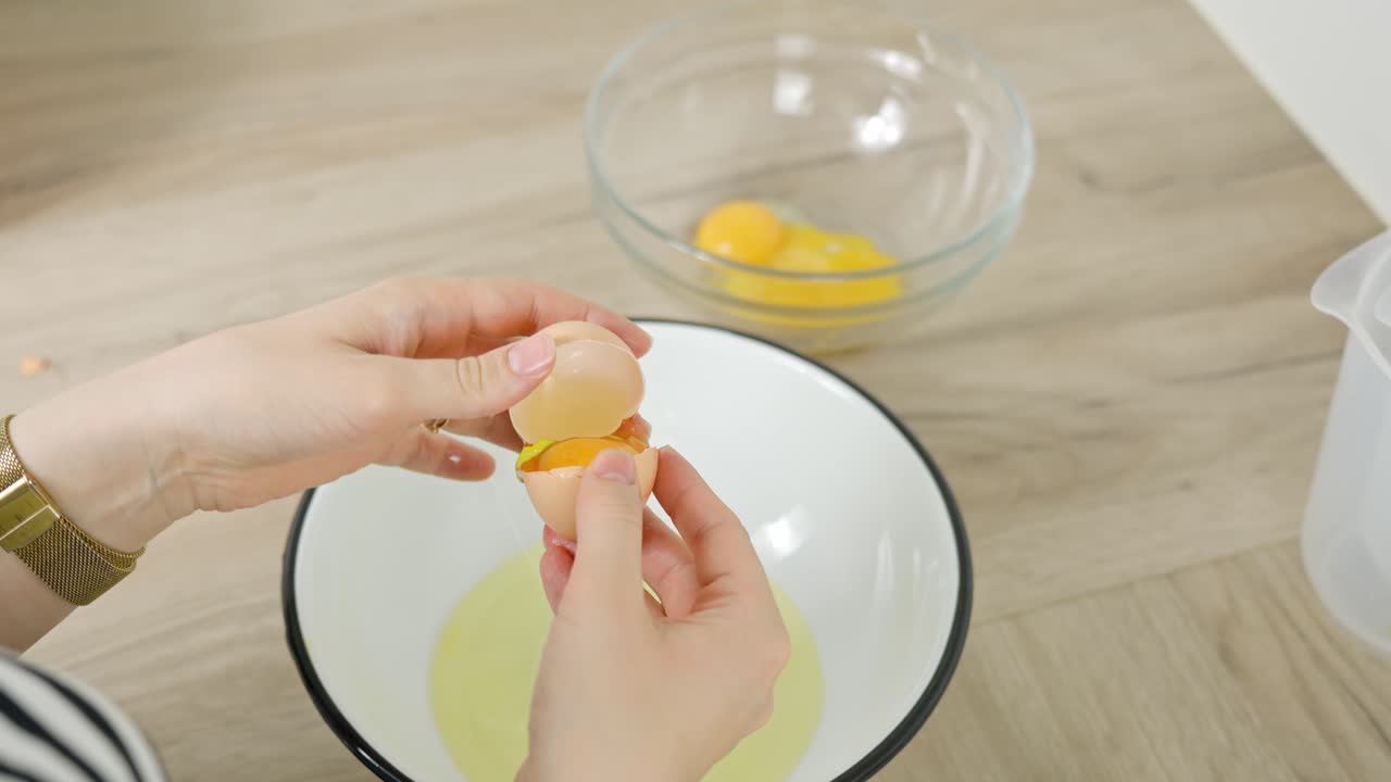 Vertical clip of egg being cracked and yolk separated for tiramisu recipe step