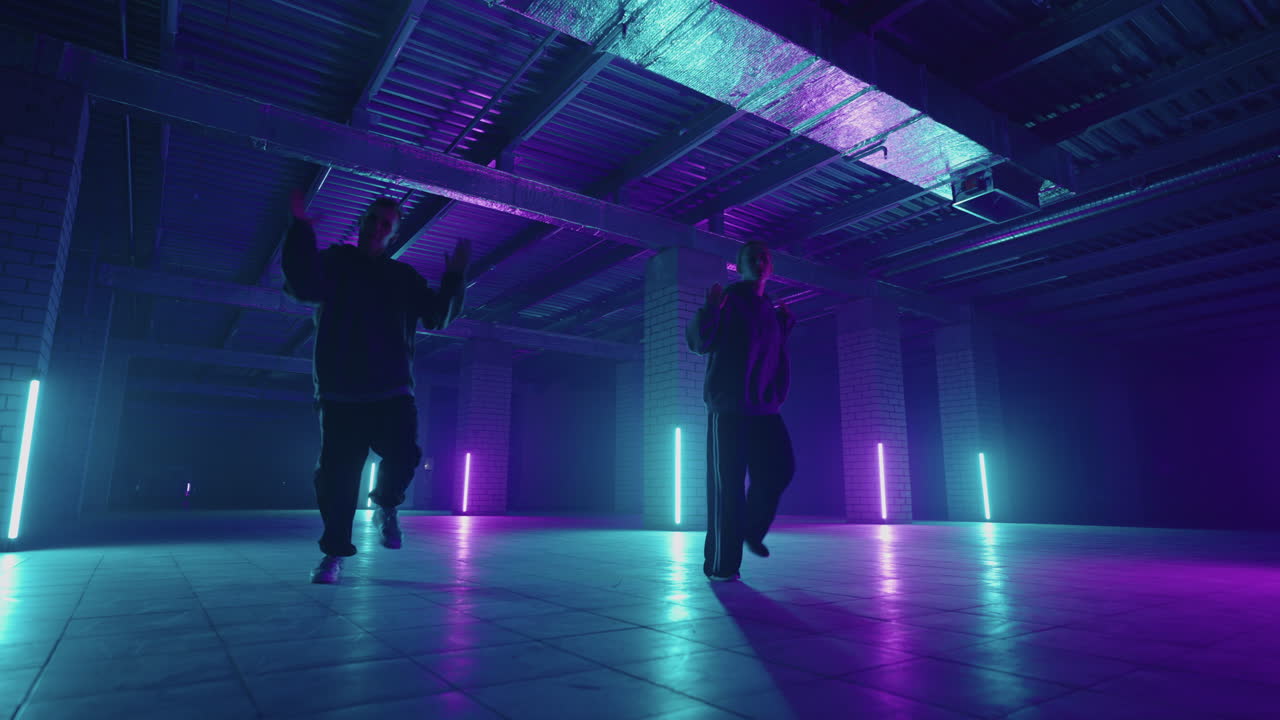 две стильные профессиональные танцовщицы-женщины и мужчины исполняют хип-хоп танцы в виртуальной среде студии производства. женщины и мужчины хип-хоп движутся в темной студии с дымом и освещением.