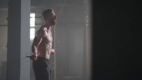 Retrato-De-Un-Joven-Atleta-Saltando-La-Cuerda.-Atleta-Masculino-En-Cámara-Lenta-Haciendo-Ejercicio-Con-Cuerda-Para-Saltar-En-Un-Gimnasio.