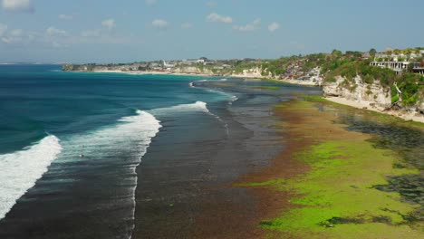 the surf spot of bingin at the cliffs of uluwatu during a sunny day. aerial shot.