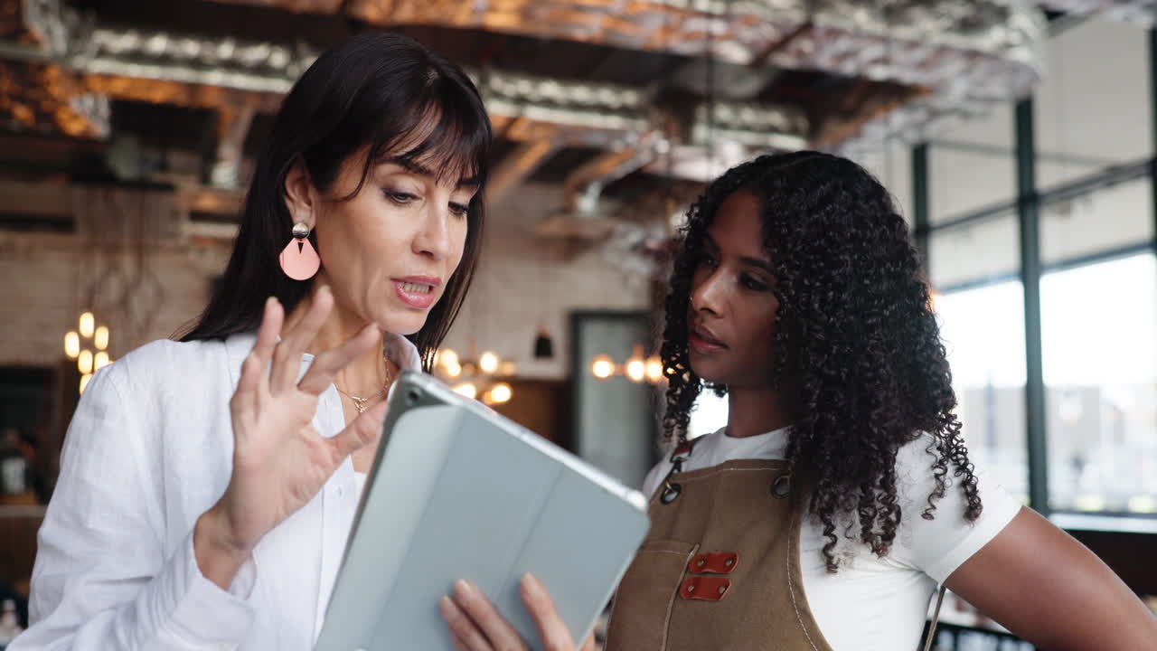 Two Women Discussing Business on a Tablet in a Cafe