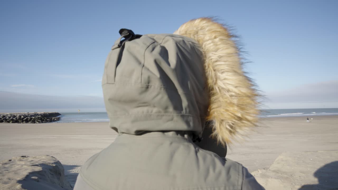 벨기에 오스텐드에서 북해 바람을 보고 느끼는 두건을 쓴 사람의 패닝 샷 - 마음 챙김, 정신, 호흡의 개념