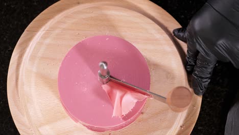 confectioner is making a petals from pink chocolate on round cutter