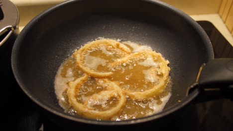 close up of huge wok while frying homemade onion rings in hot oil and deep pan