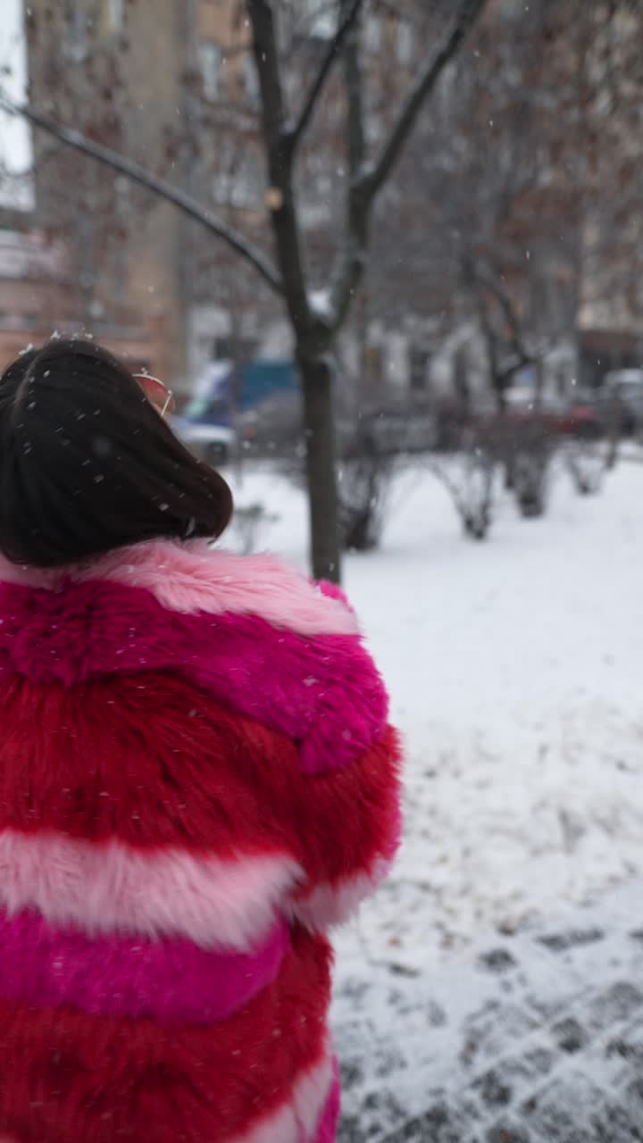 mujer con un colorido abrigo de piel disfrutando de un día nevado en la ciudad