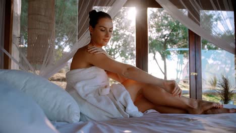 woman applying lotion while sitting on canopy bed 4k