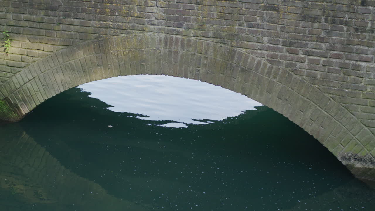 벽돌 다리의 중간 클로즈업 샷, 다리 아래로 흐르는 푸른 강