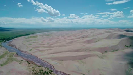 Drohnenblick-Auf-Weiche-Sandberge-Und-Einen-Fluss-In-Colorado