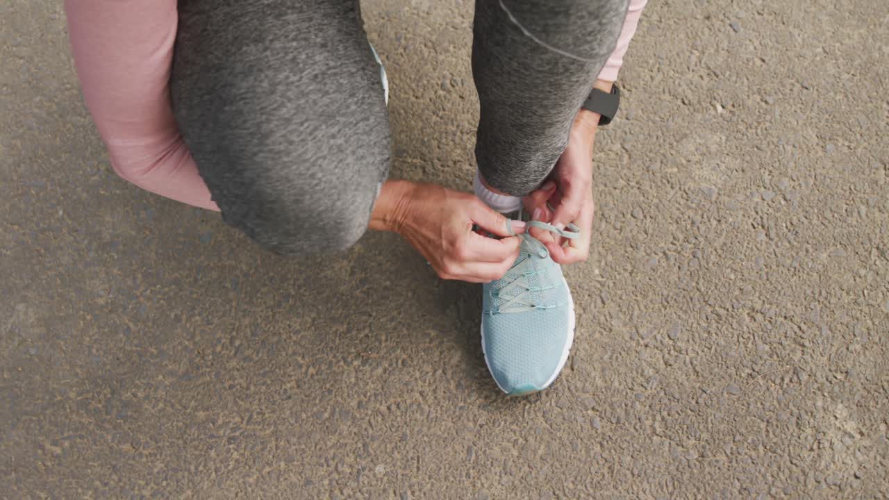 Chiuda in su della donna che lega i lacci delle scarpe