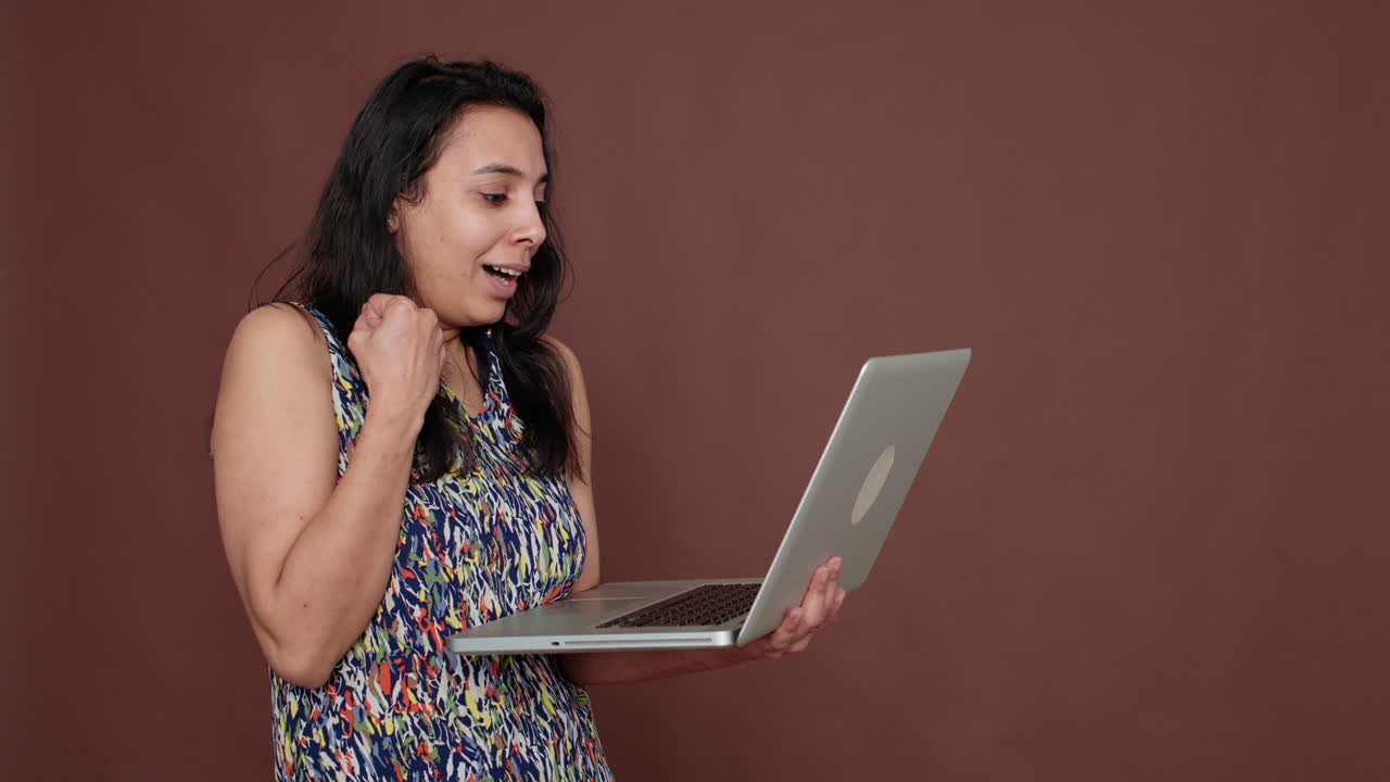 Happy female model holding laptop computer on camera