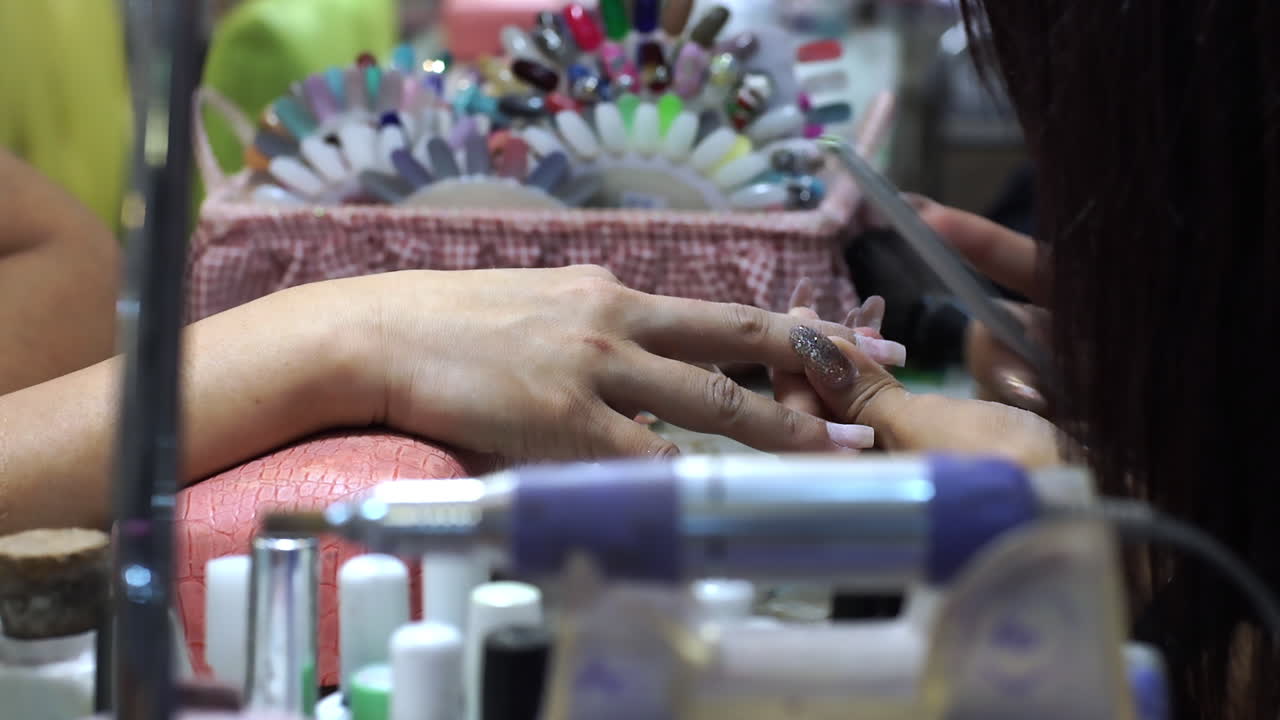 Close-up of a woman receiving a professional hand and nail manicure at a beauty salon. Focus on female hands, skincare, and nail care treatment