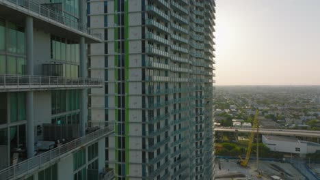 tight forwards flight along modern high rise apartment buildings. revealing large flat area view residential urban boroughs against sunshine. miami, usa
