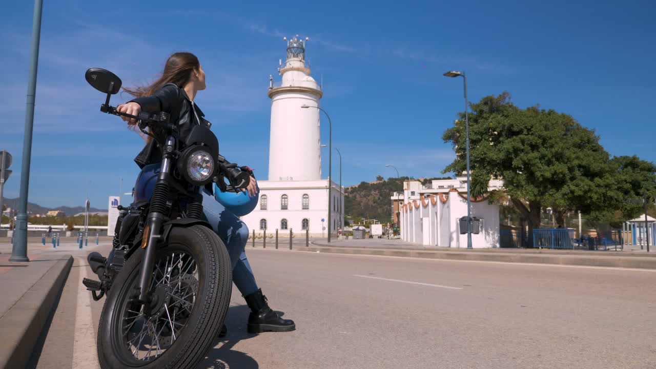 una hermosa motociclista apoyada en su superbike en la calle en un día soleado