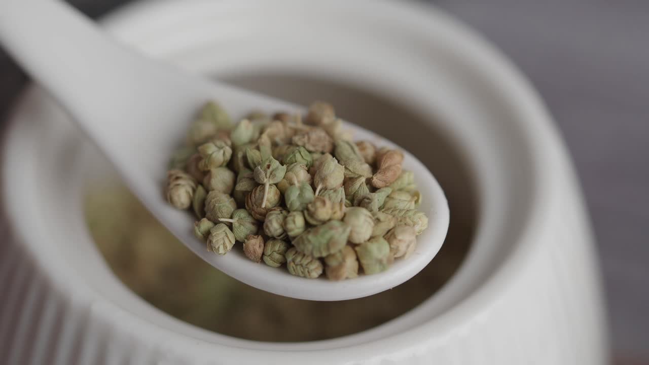 Close-up of dried herbs or spice buds on a white spoon