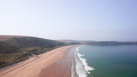 wide aerial flyover of a large sandy beach on a perfect summer’s morning