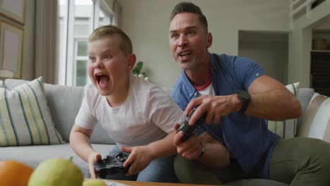 Feliz-Padre-Caucásico-Con-Su-Hijo-Sentado-En-La-Sala-De-Estar-Y-Jugando-Videojuegos