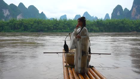 cute chinese hanfu girl posing on bamboo raft in li river, xingping