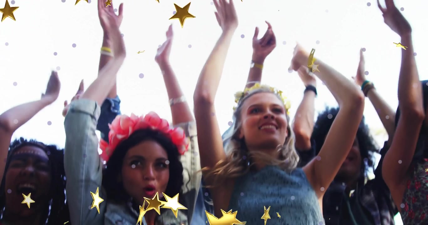 Partecipanti al festival che alzano le braccia, facendo volteggiare coriandoli a forma di stella dorata tra un gruppo che applaude all'unisono