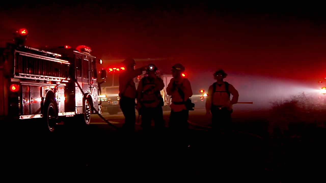 los bomberos discuten la estrategia alrededor de sus camiones durante el incendio festivo en goleta california
