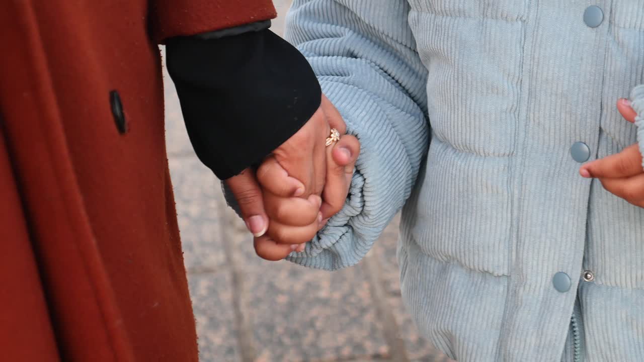 madre e hija tomadas de la mano