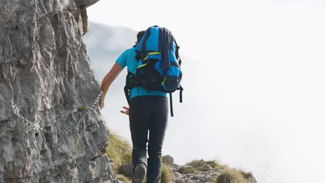 Hiker-Using-Chain-Safety-Rope-On-Mountain-Side-Path-In-Lecco-Alps