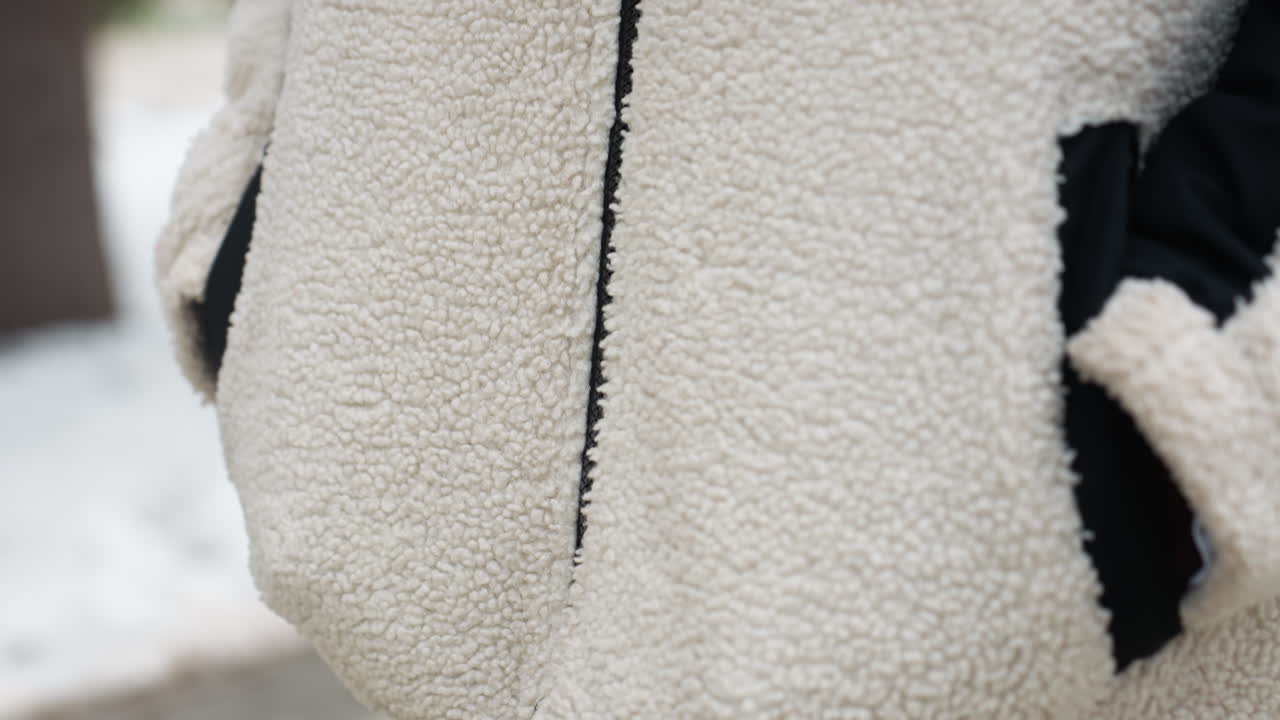 편안한 겨울 재 텍스처의 클로즈업, 주머니에 손을 넣고, 지퍼와 직물을 상세히 설명하여 겨울 산책 중에 따뜻함과 스타일을 강조합니다.