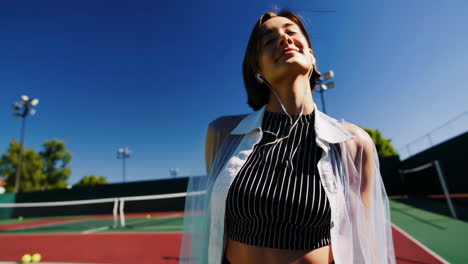 young woman enjoying music on a sunny tennis court