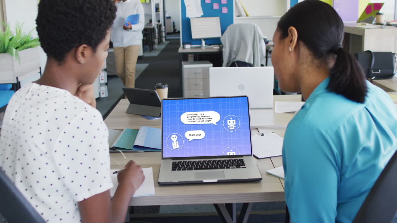 Diverse businesswomen in office using computer with ai digital messaging chat on screen