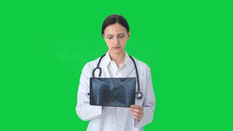 serious indian female doctor checking x ray green screen