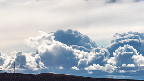 huge cumulus clouds forming and evolving above the silhouette of the mojave desert and a cellular tower - time lapse