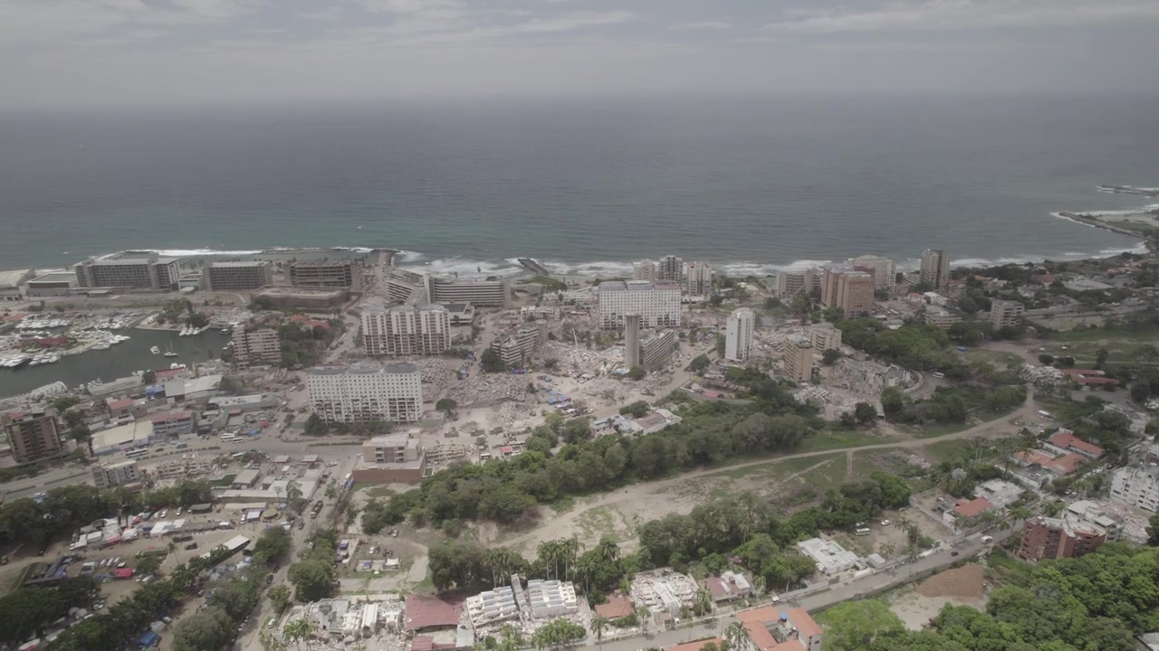 Panoramica aerea verso destra che rivela il contrasto tra i quartieri danneggiati dal terremoto e quelli sopravvissuti a Caraballeda, La Guaira, Venezuela. Video 4k Dlog