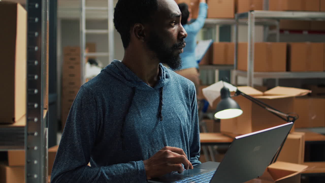 Man working on laptop in warehouse with boxes