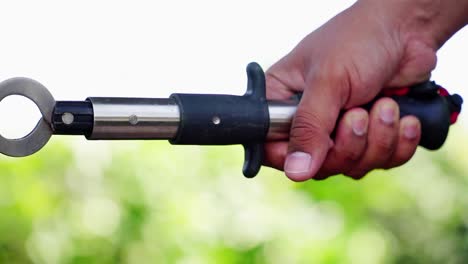 hand is holding lip grip of fishing tool with nature blur background