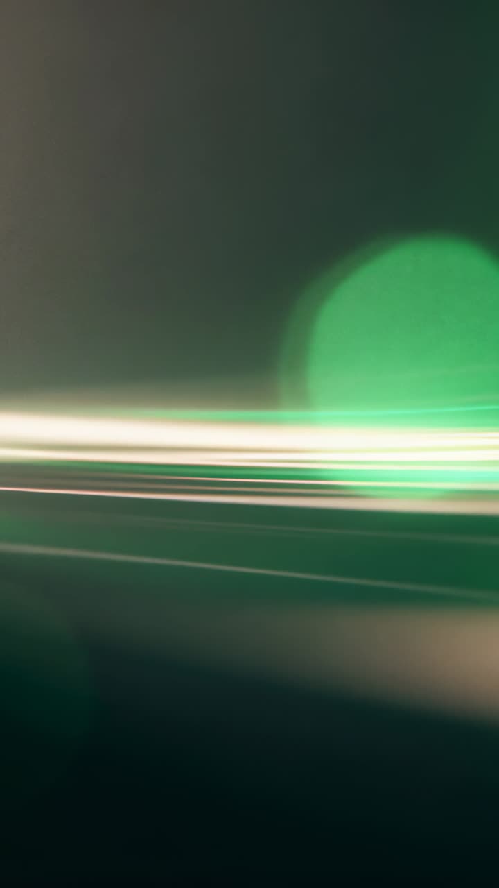 Video verticale: La telecamera si sposta mostrando scie di luce e bokeh verde che si muovono attraverso uno studio buio.