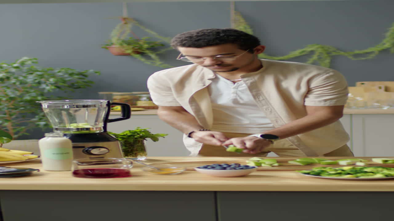 Man Putting Green Apple in Kitchen Blender