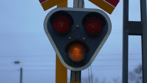 a yellow blinking light at a train track intersection signaling caution - close up