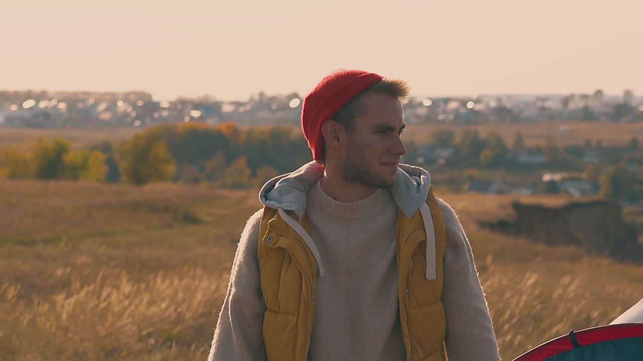Smilende fyr retter på orange hat og går væk på gul eng.