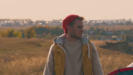 smiling-guy-fixes-orange-hat-and-walks-away-on-yellow-meadow