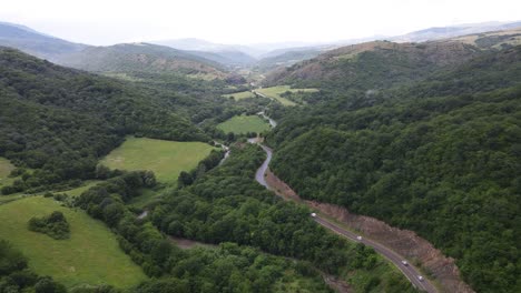 Aerial-view-of-mountains-village-country-road-in-beautiful-green-meadows-mountains