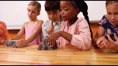 School-kids-looking-at-specimen-stone-through-magnifying-glass-in-laboratory