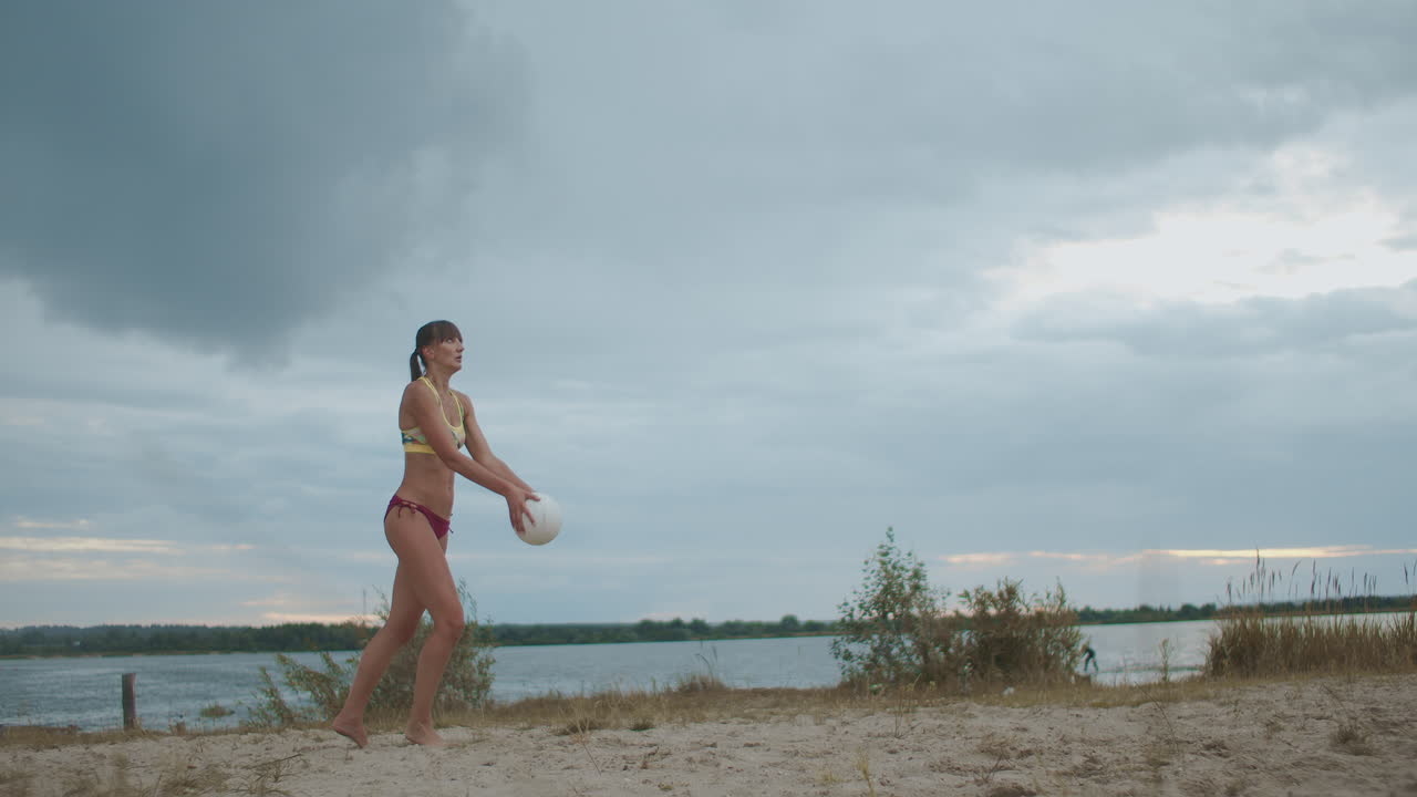 спорт и энергия пляжный волейбол игрок женщина служит мяч прыжок на песчаный корт и ударный мяч