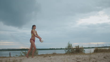 sport and energy beach volleyball player woman is serving ball jumping on sand court and striking ball