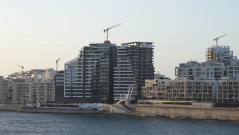 modern buildings and cranes in malta. urban seaside resort town sliema